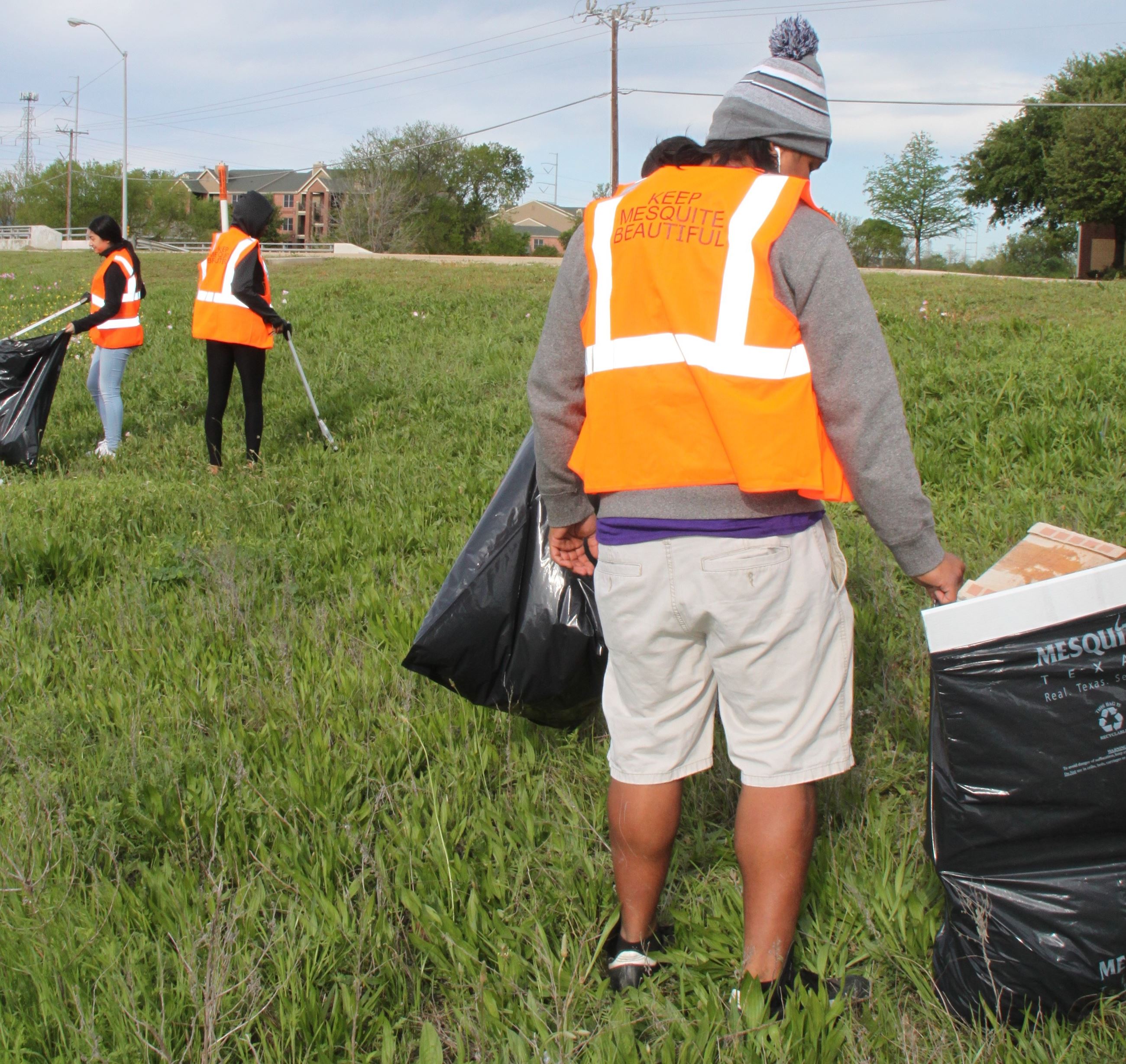 Trash bash man in orange vest picking up trash
