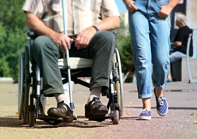woman walking next to man in wheelchair