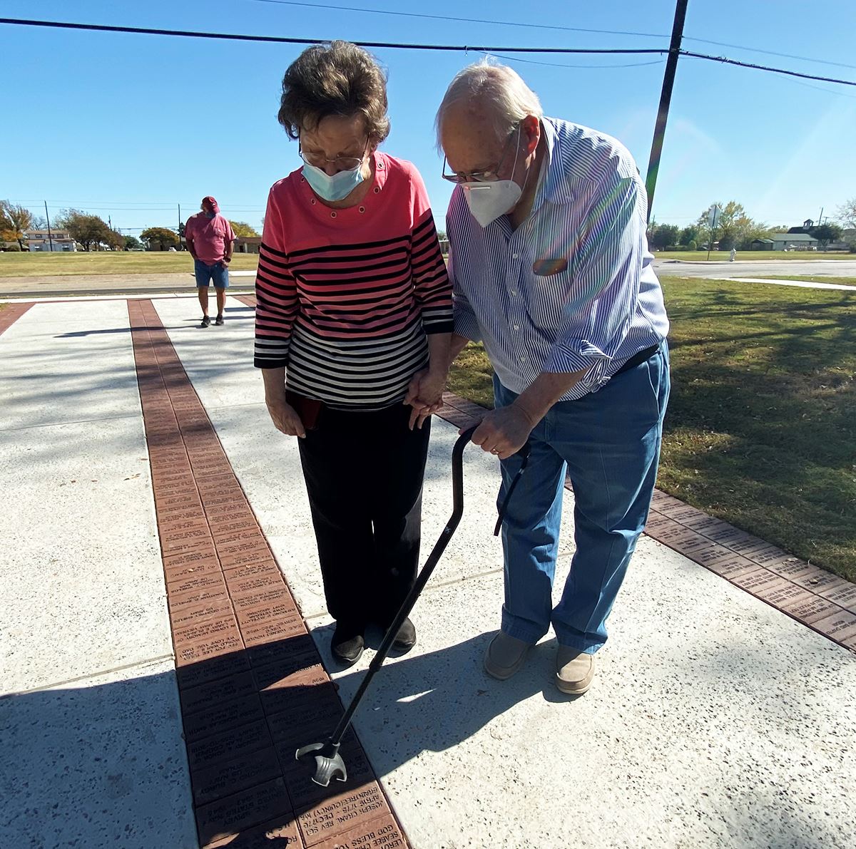 Military veteran couple holds hands and points to their brick on the Walk of Honor at Mesquite Veter