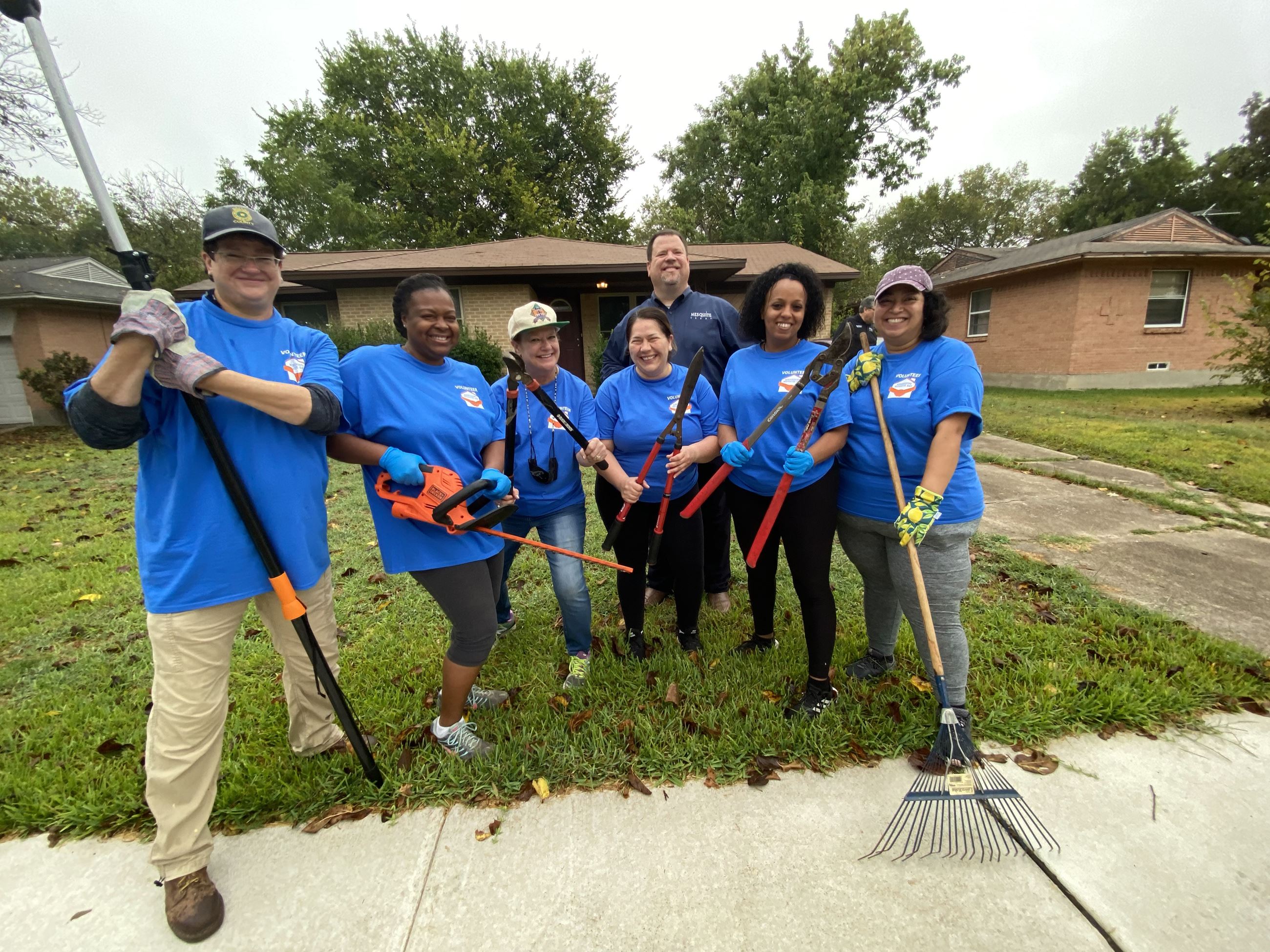 mayor and volunteer group pose in front of house