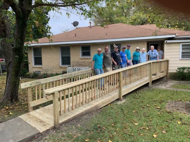 group poses on ramp they built and homeowner